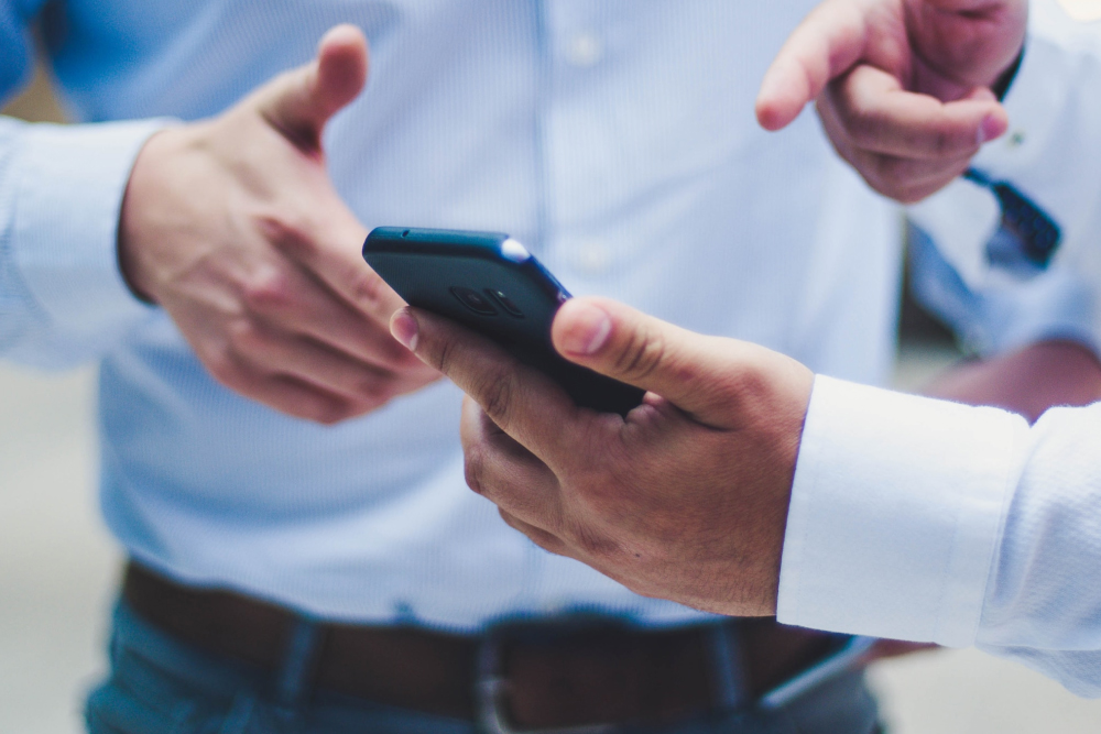 Two men reviewing digital ad on their mobile device.